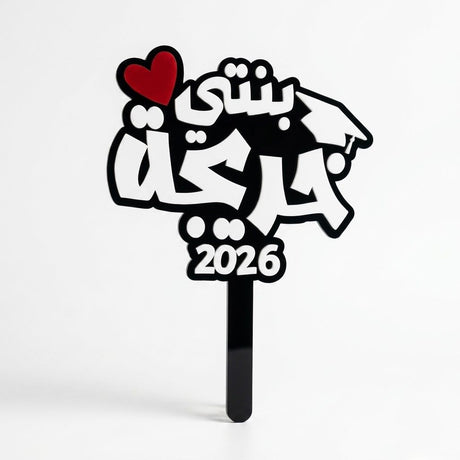 Black and white acrylic graduation topper reading "بنتي احلى خريجة", suitable for flower bouquets and graduation photo props in UAE